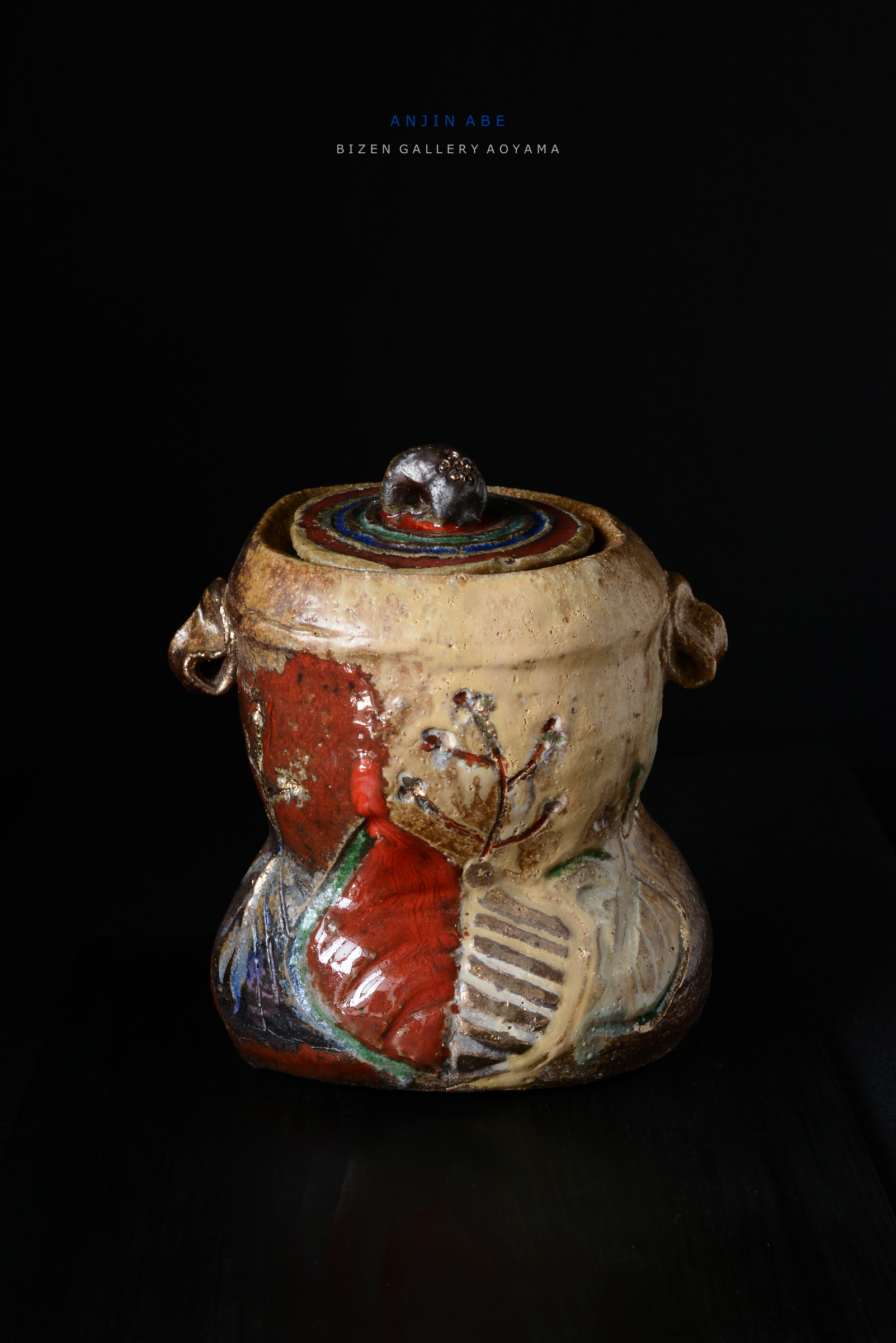 Artistic ceramic vase with a colorful lid and intricate designs, displayed against a dark background.
